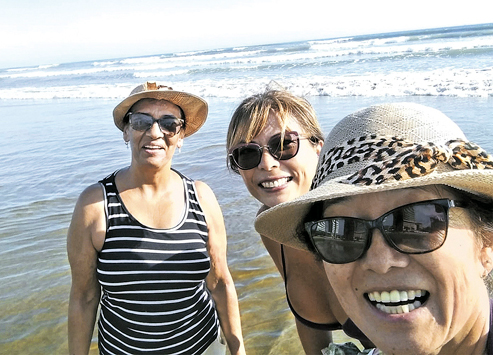 Sueli, à dir., caminhando com amigas na orla da praia